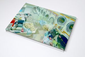 Bird's eye view of front cover of "Surveillance" book laying on white surface